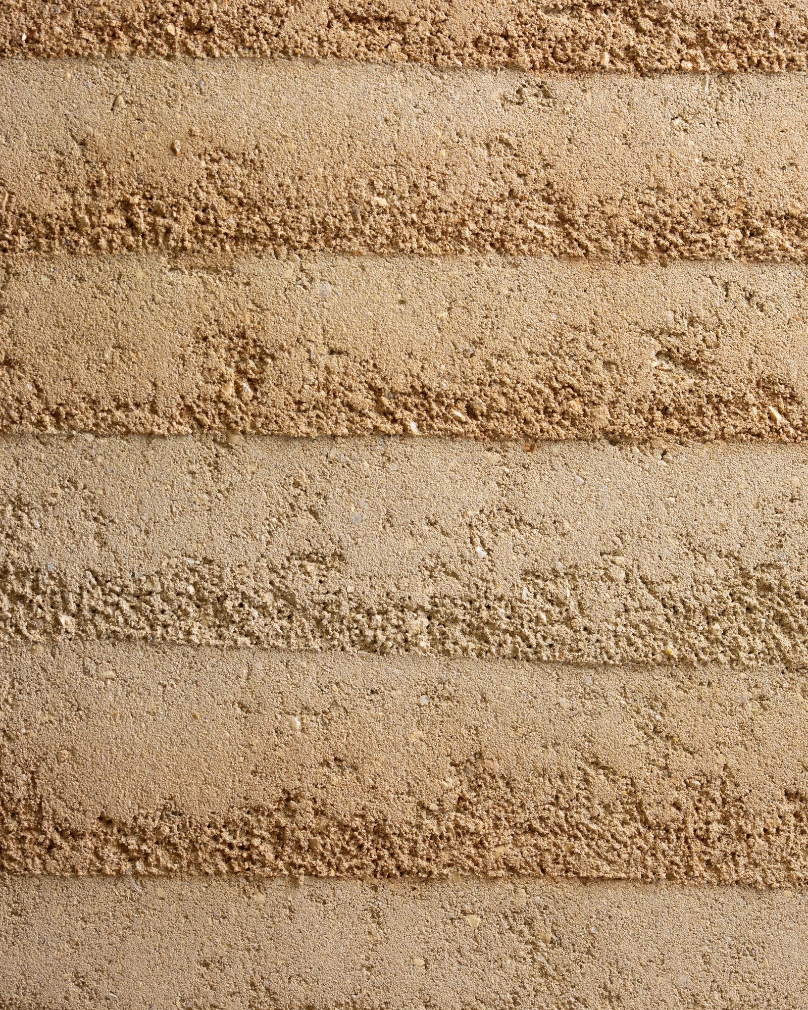 Rammed earth finish texture showing horizontal strata banding in warm earth tones