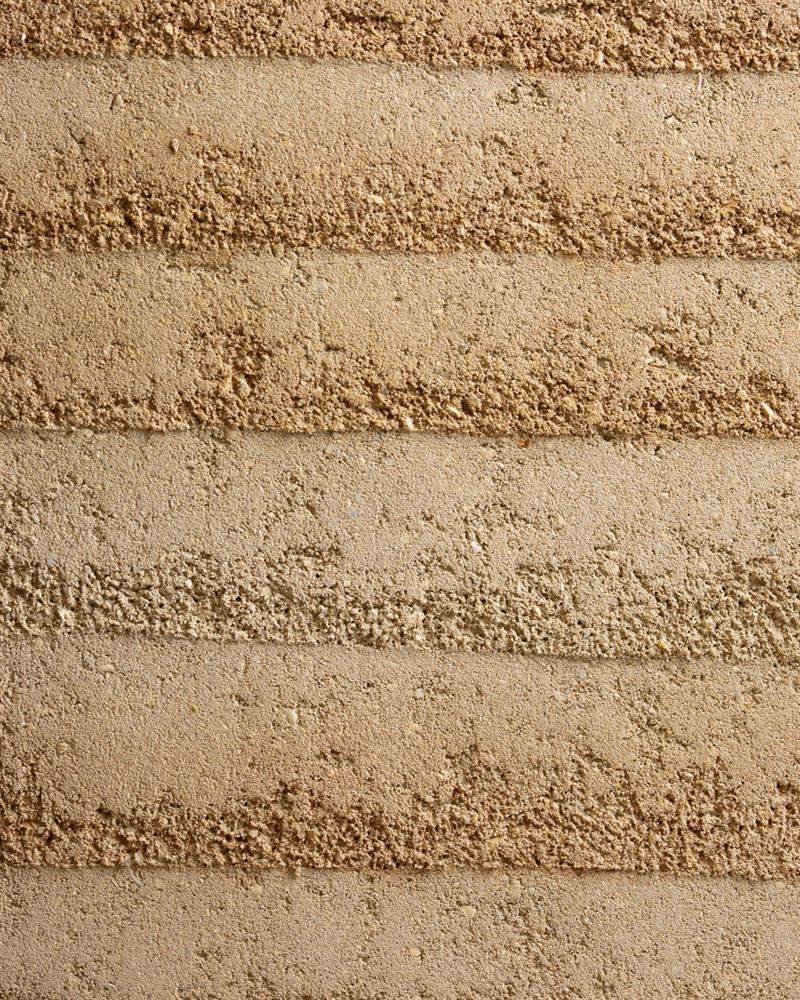 Rammed earth finish clay plaster showing horizontal strata in warm earth tones