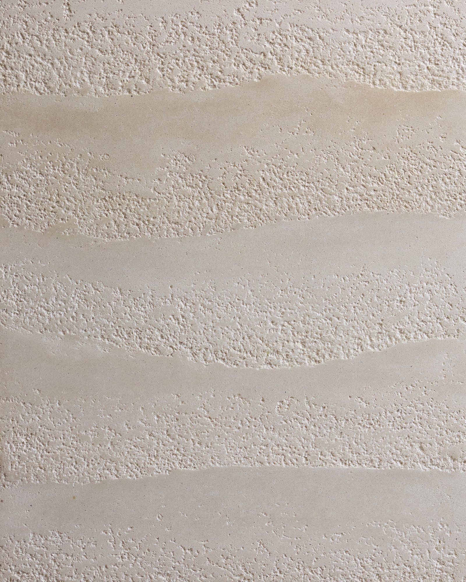 Rammed earth surface with open grain and graded aggregate.