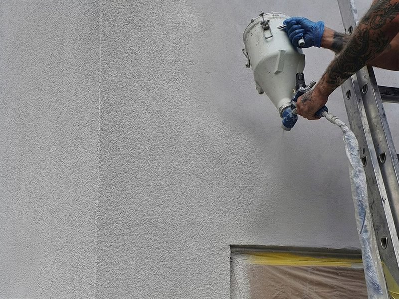 Projected cork being spray-applied to a facade