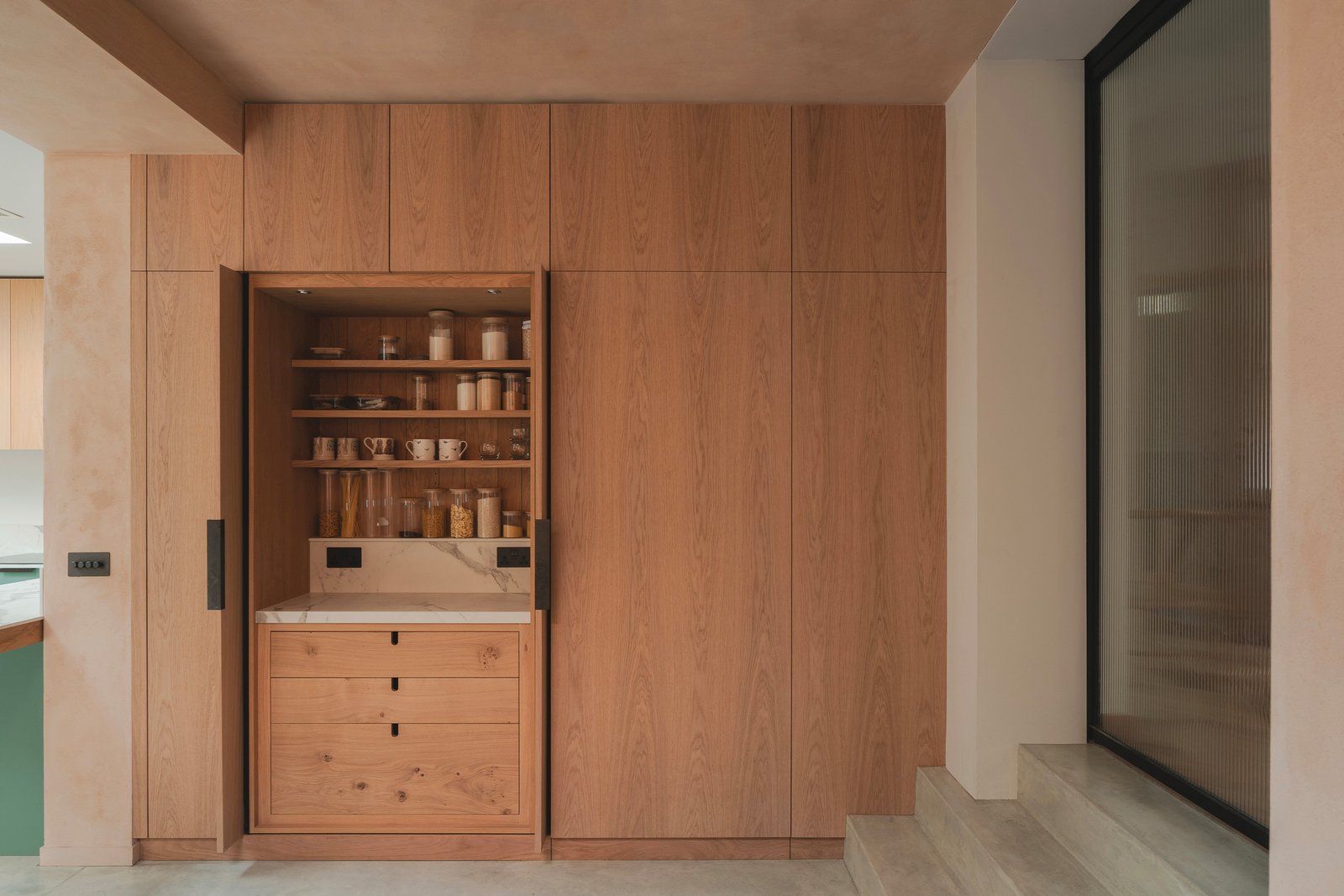 Ground-floor extension at Balmore House, London, with clay-plastered walls and glazed sliding doors to the garden.