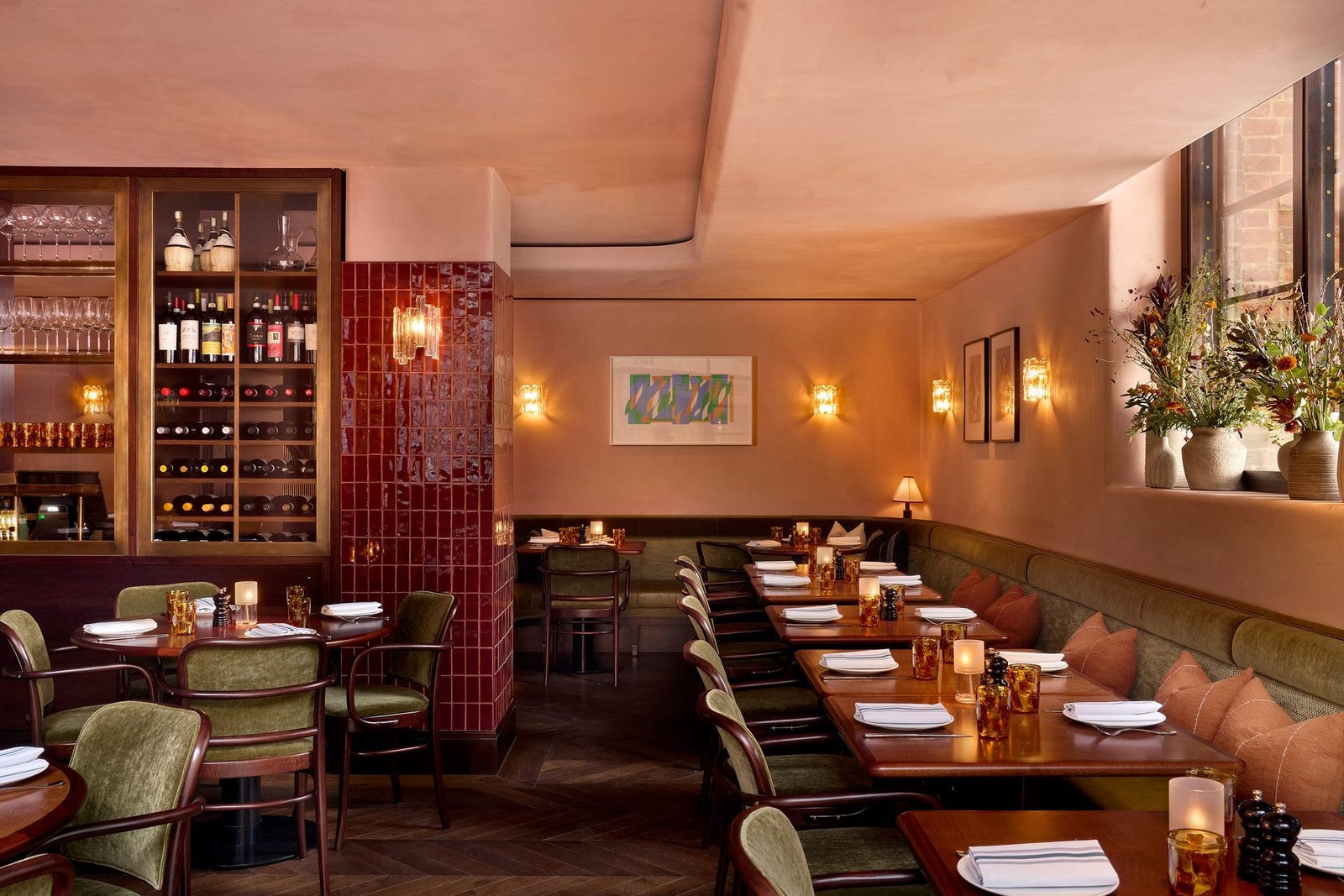 Nipotina bar room: wine cabinetry, an oxblood tiled column and clay-plastered walls above olive banquettes.