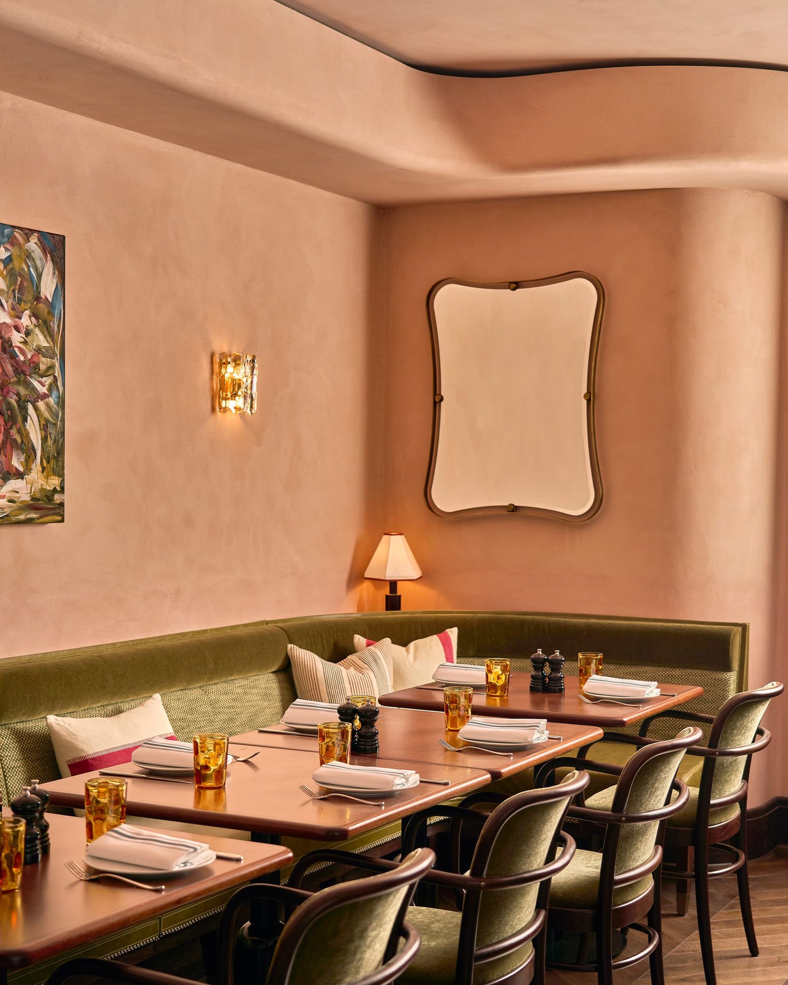 Corner at Nipotina with a shaped mirror and glass sconce on smooth clay plaster above olive velvet seating.