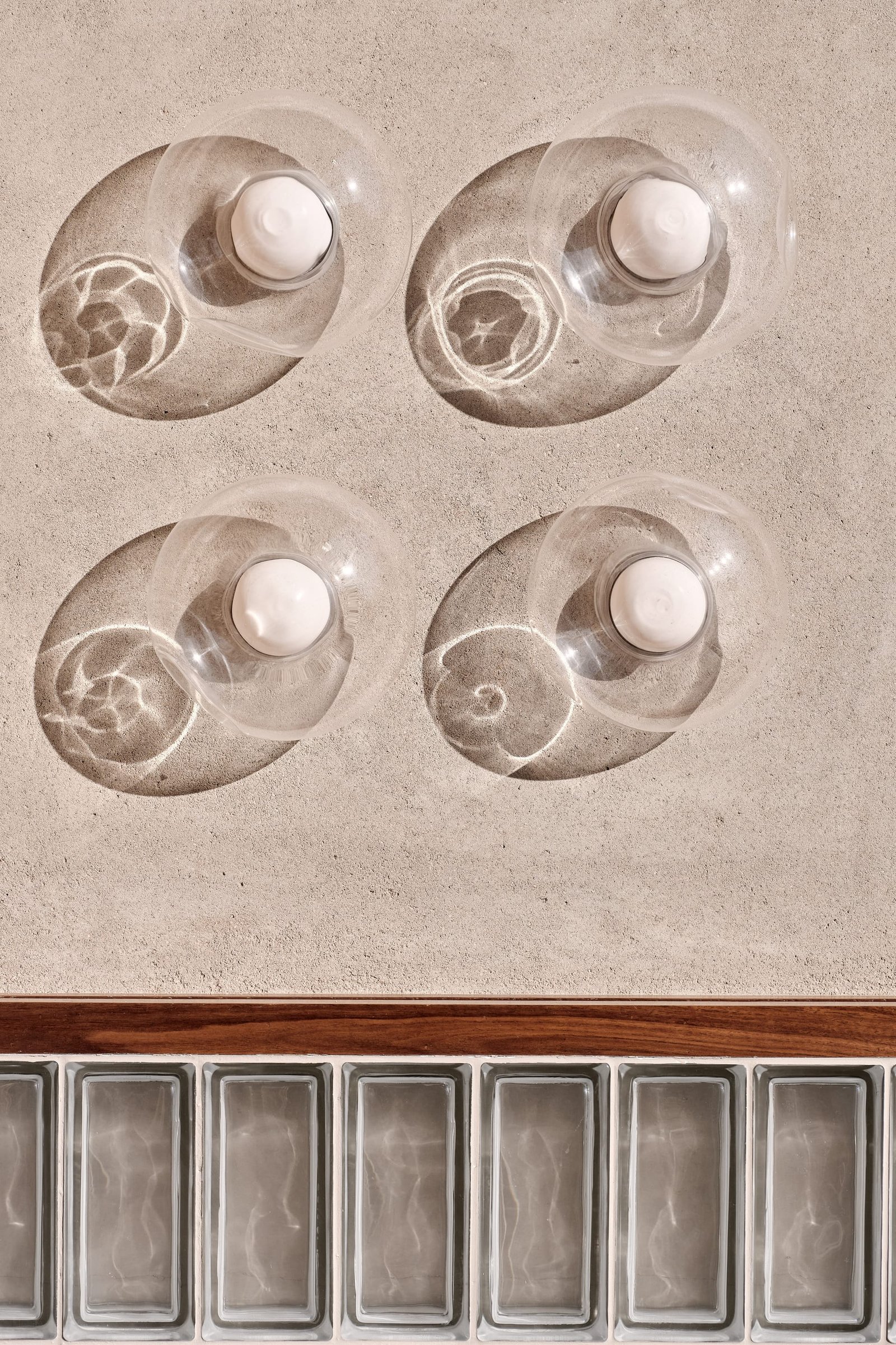 Glass wall lights set against Demi Rustic clay plaster above a band of glass block at Toplum.