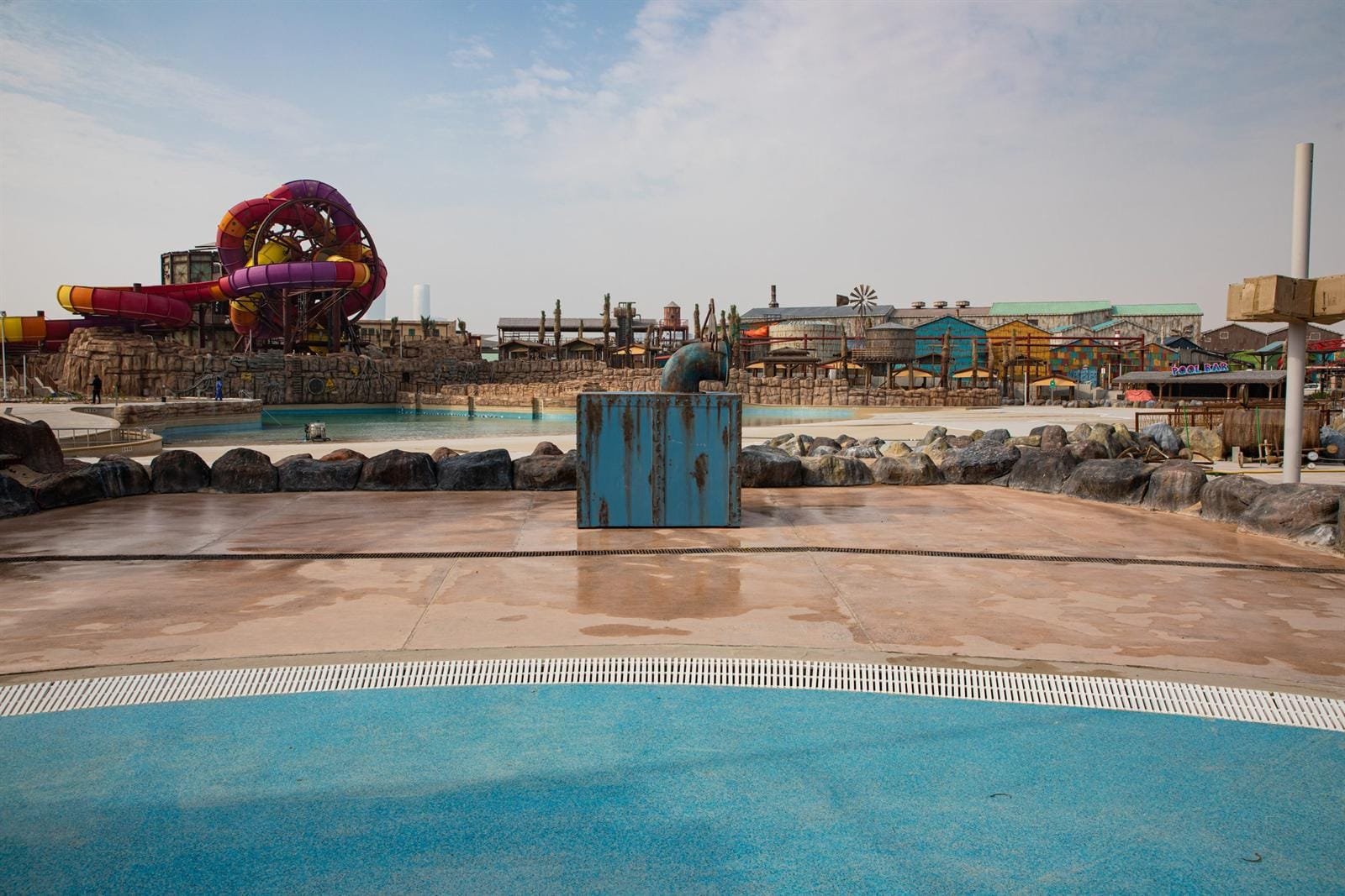 Circular turquoise splash pad ringed by a rose-pink Exposed Plus deck at Meryal Waterpark, Qetaifan Island