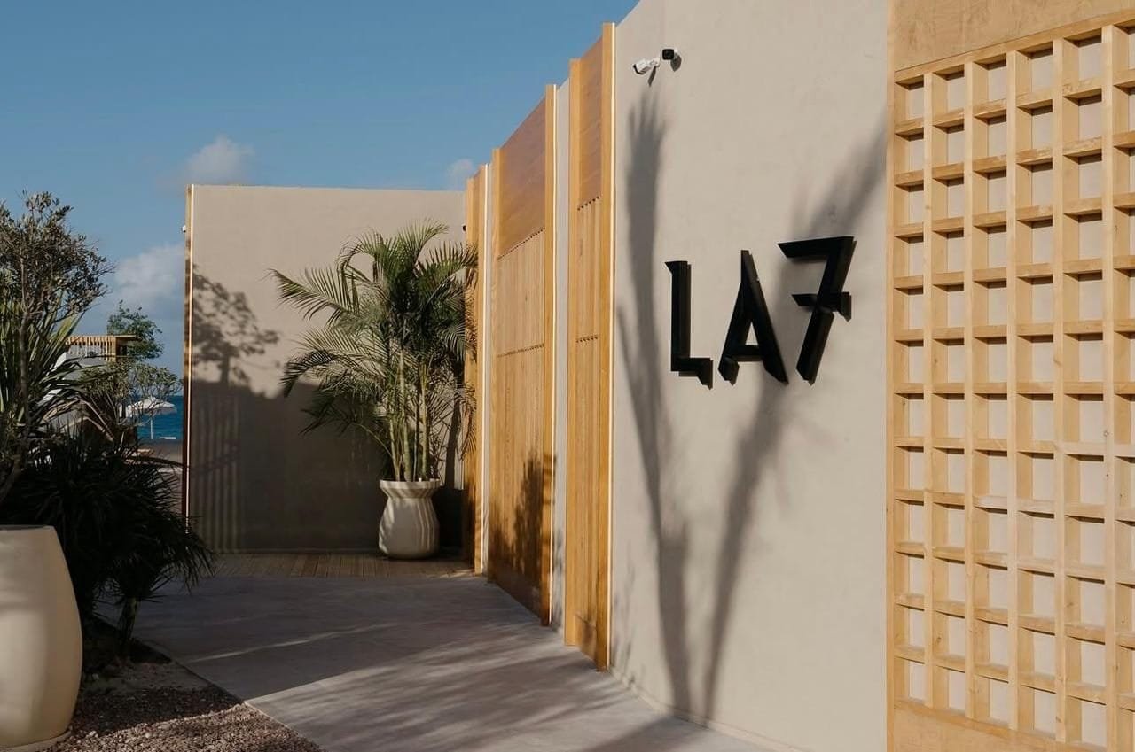 Entrance at LA7 Wellness Beach Club, Egypt, black lettering on a sand-toned microcement wall between timber screens