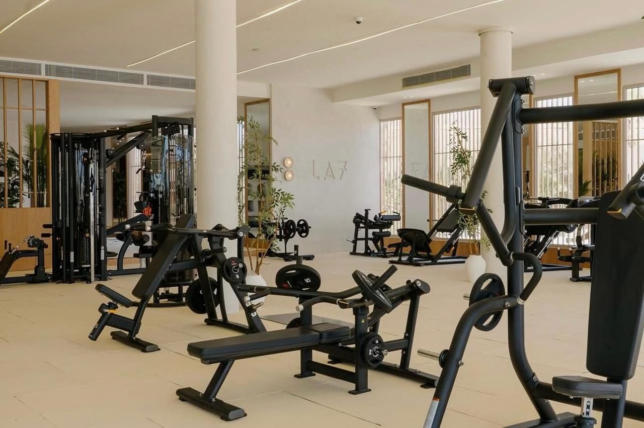 Pale seamless microcement floor in the free-weights gym, LA7 Wellness Beach Club