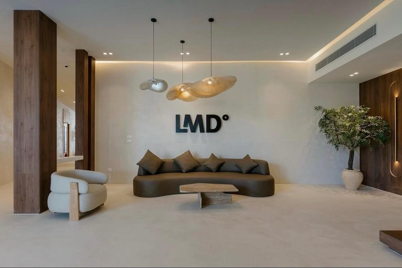 Sand-toned microcement surfaces and built-in joinery in the sales centre lobby at LA7, Egypt