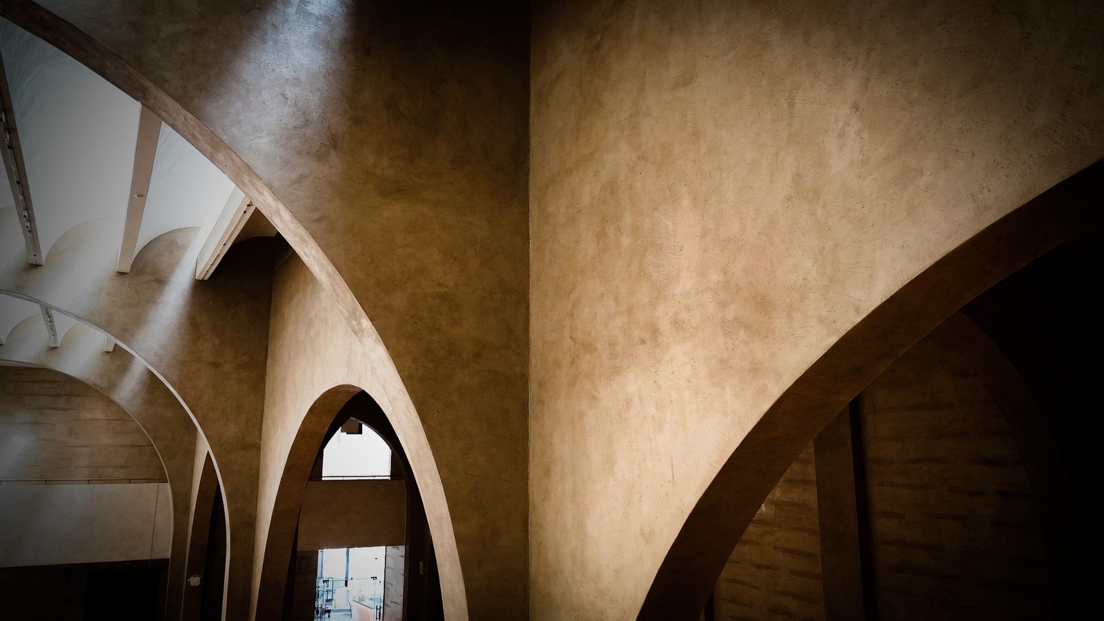 Intersecting polished sand tadelakt arches with warm reflected light at the Calligraphy Museum, Madinah