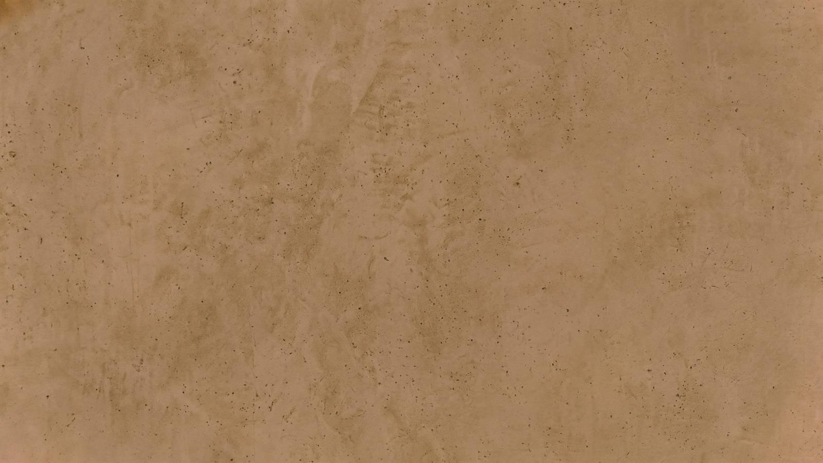 Full-frame close-up of the same speckled sand plaster surface in a warmer caramel grade, pinhole pores and trowel clouding