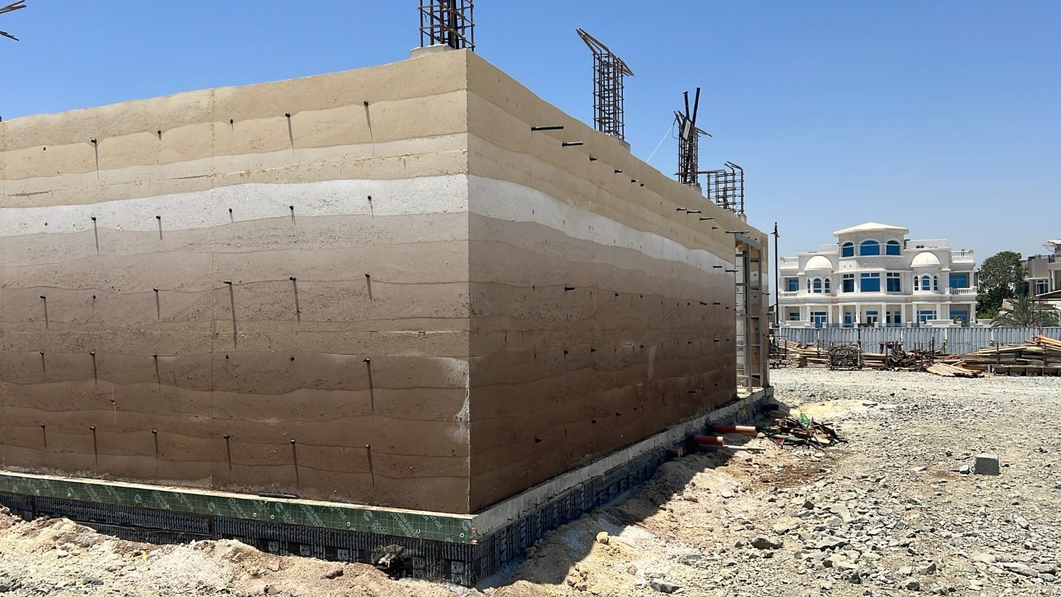 Completed in-situ rammed earth wall, tamped lifts banding cream to brown, Kalba Beach