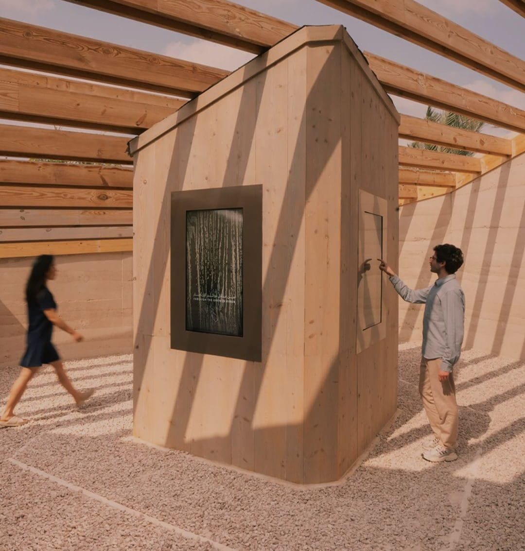 Visitors at the UAE Pavilion, Expo 2023 Doha, beneath the timber structure set against in-situ rammed earth walls