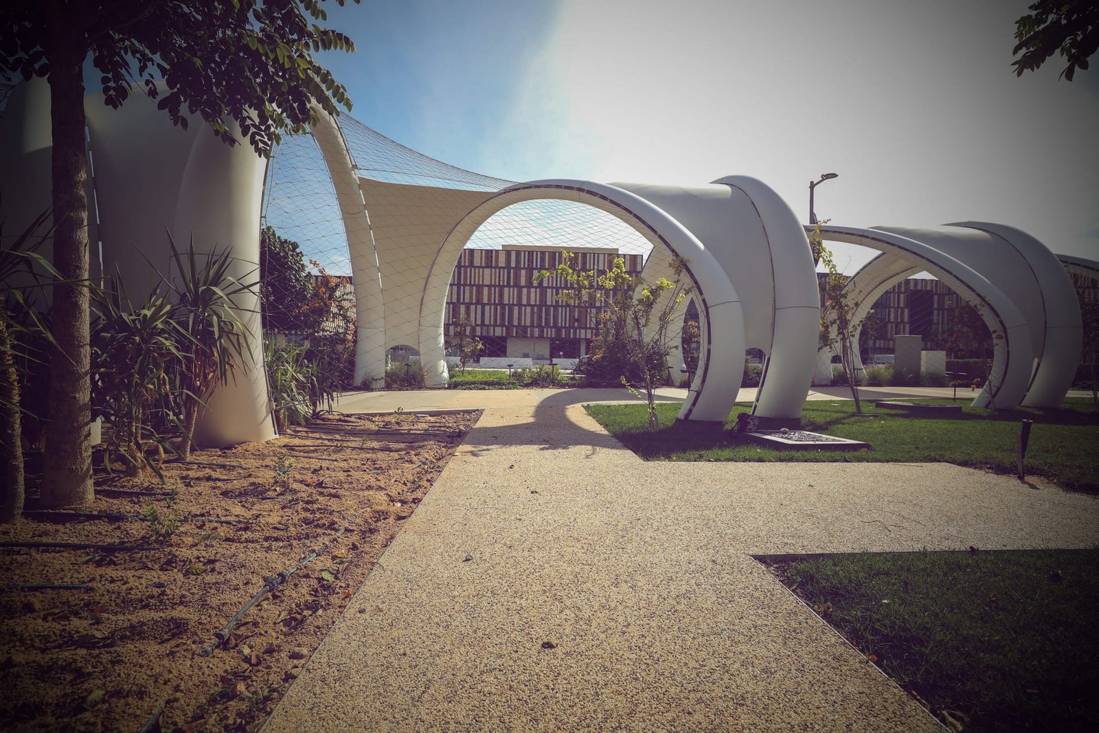 Resin bound aggregate promenade paving under arched canopies in strong Gulf sunlight