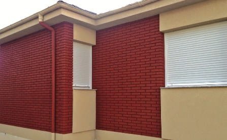 Red brick effect projected cork between cream rendered columns on a house facade