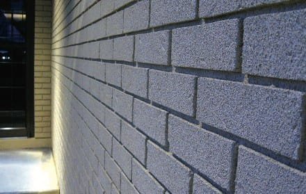 Grey projected cork over a brick wall lit at night, the brick coursing still legible
