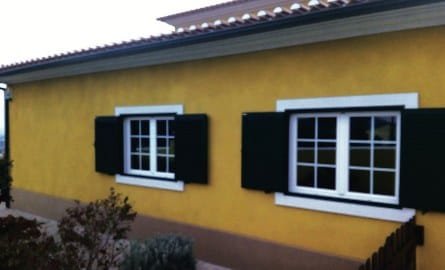 Yellow projected cork facade with white window surrounds and dark green shutters