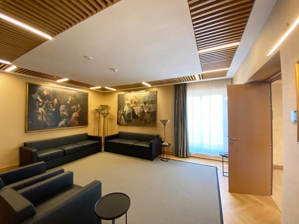 Meeting room at Banca d Italia, Rome, with old master paintings and a flush plaster ceiling panel framed by timber slats