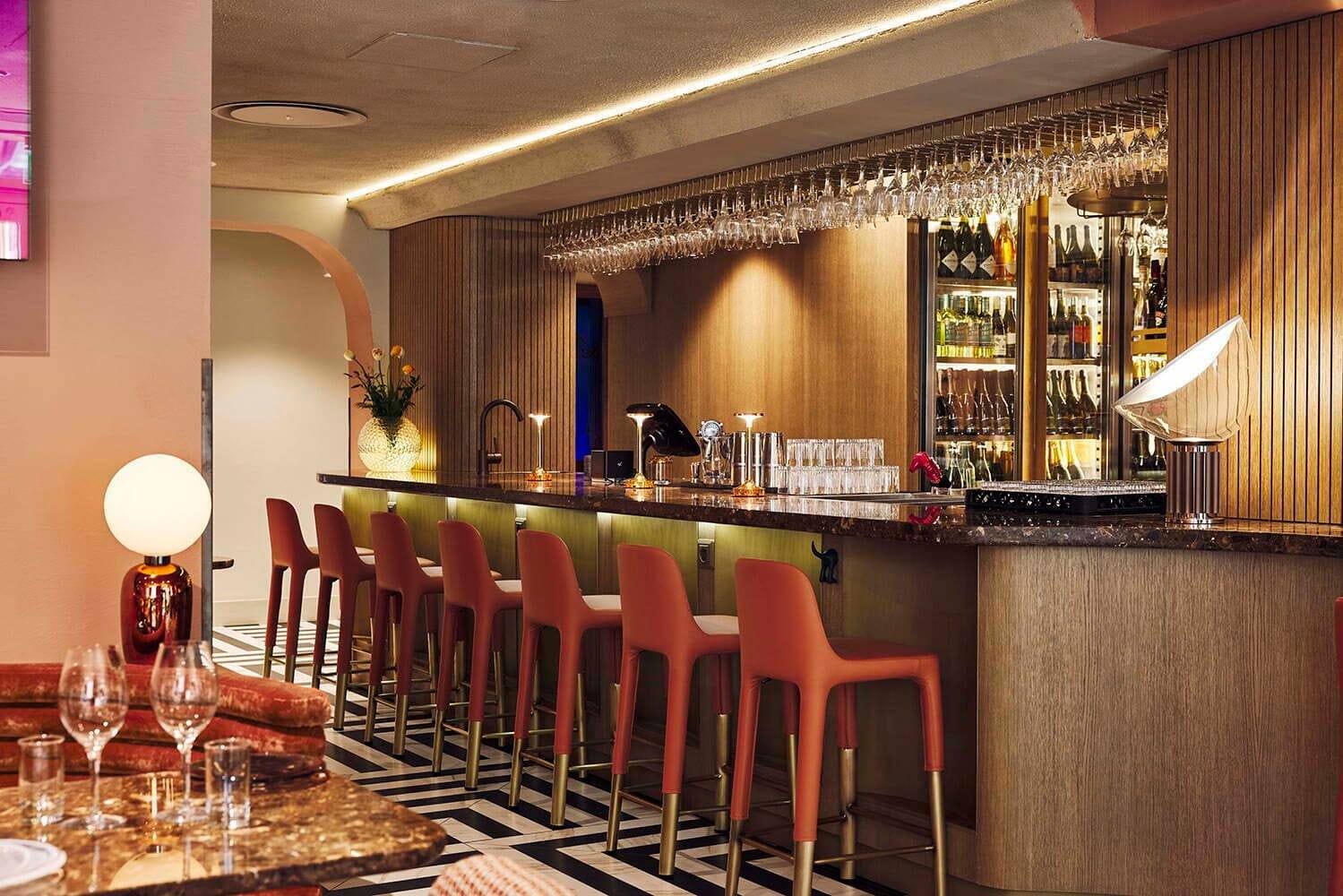 Bar at Melody Club, London, with a seamless acoustic ceiling and terracotta stools on a striped marble floor