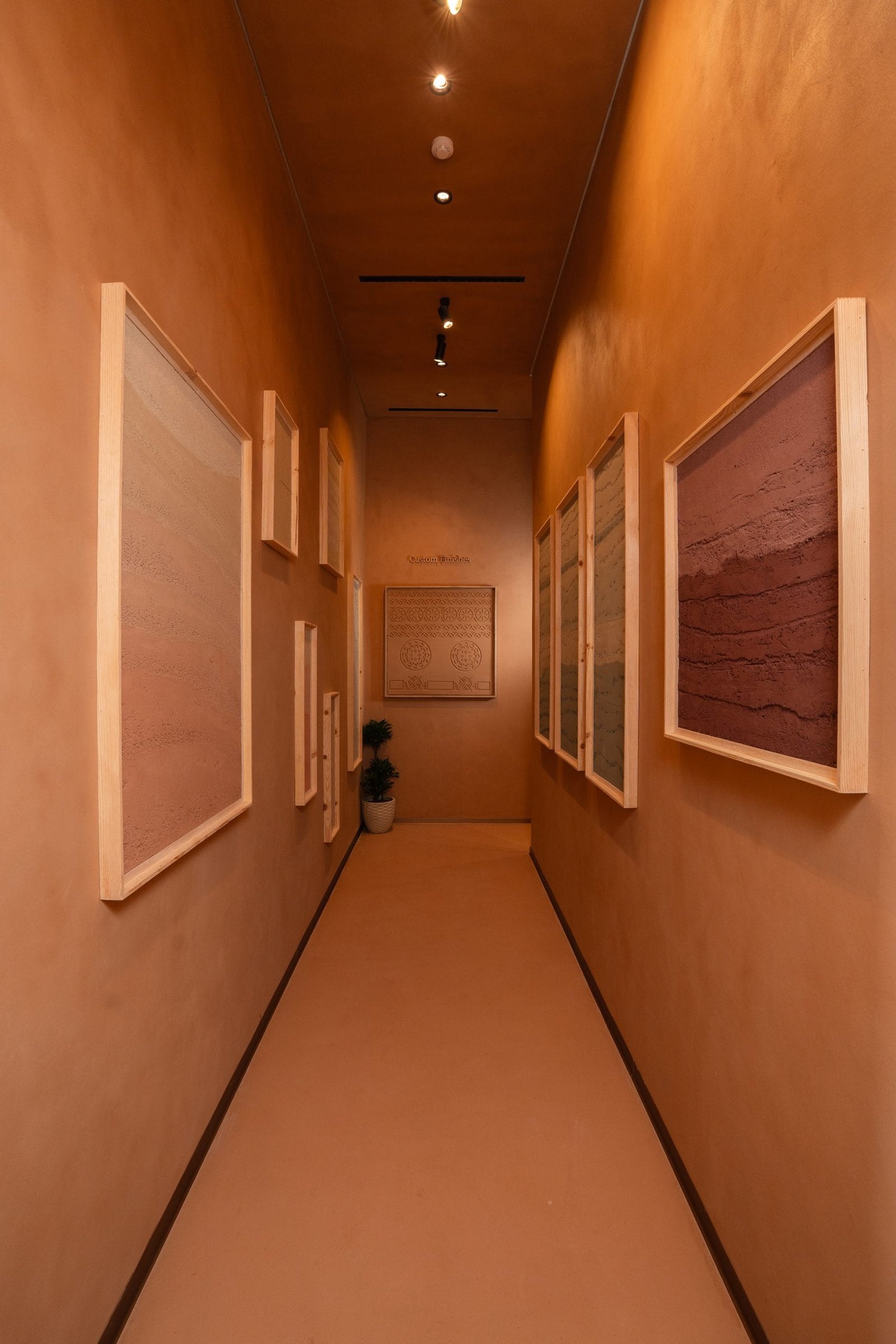 Sample corridor at the Conmarble showroom looking toward the Custom Finishes panel, framed clay plaster boards down both walls.