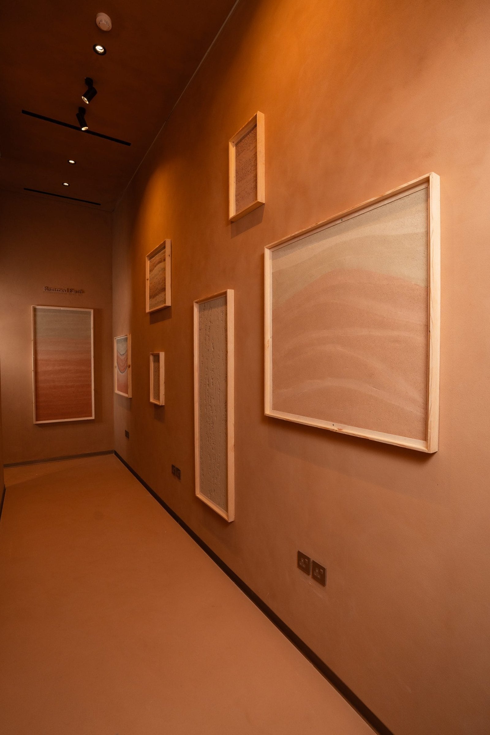The Clay and Smooth arched sample walls at the Conmarble showroom, framed clay plaster boards including carved geometric and camel motifs.