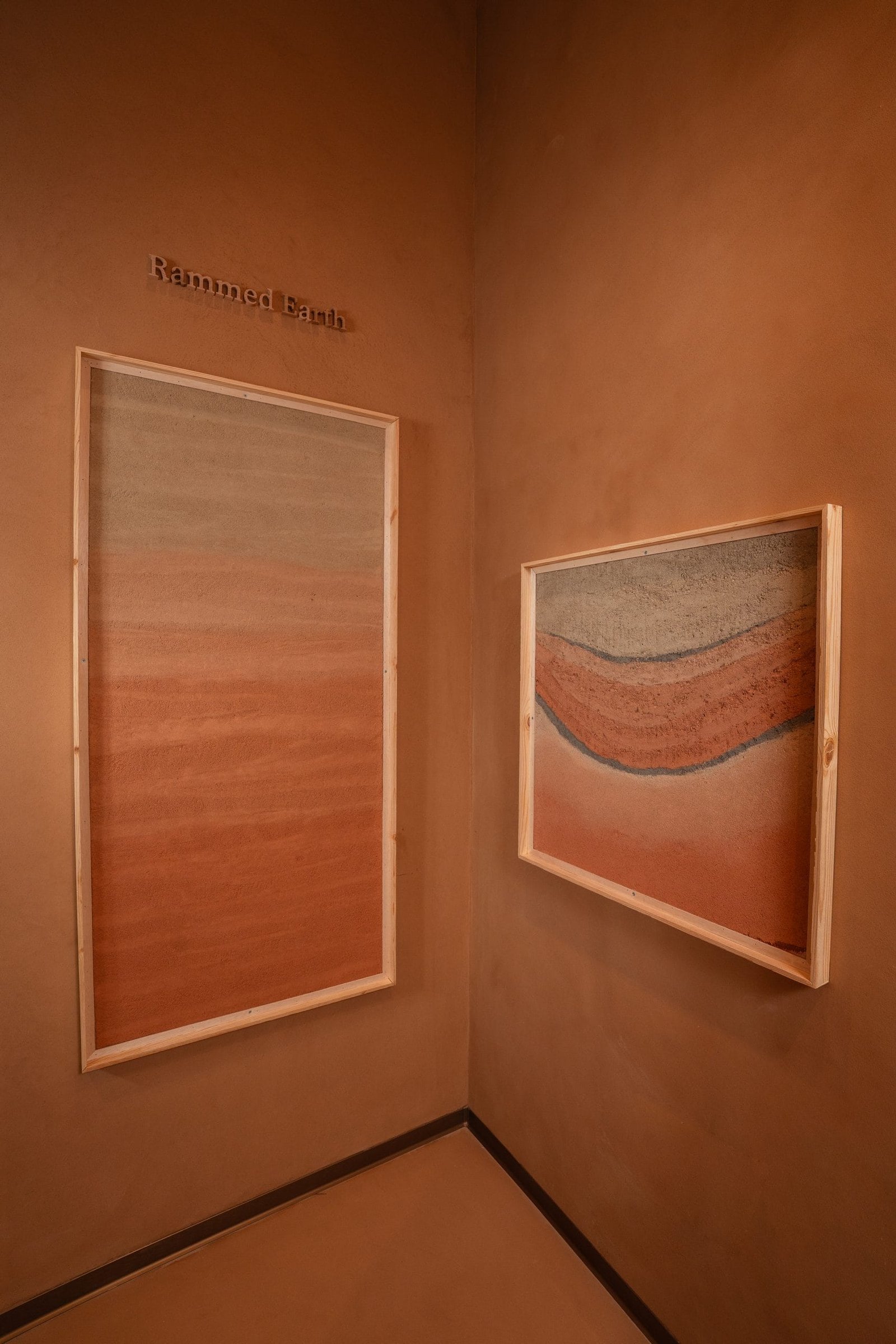 Corner of the sample gallery at the Conmarble showroom with framed rammed earth plaster panels stepped along the clay-plastered wall.